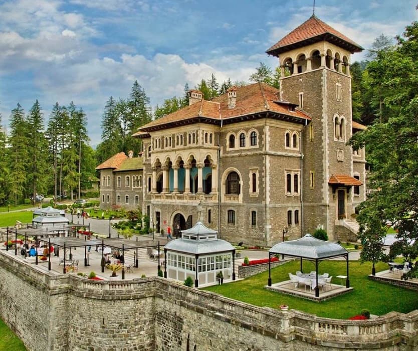 Cantacuzino Castle's stone facade, tower, and garden terraces at Bușteni