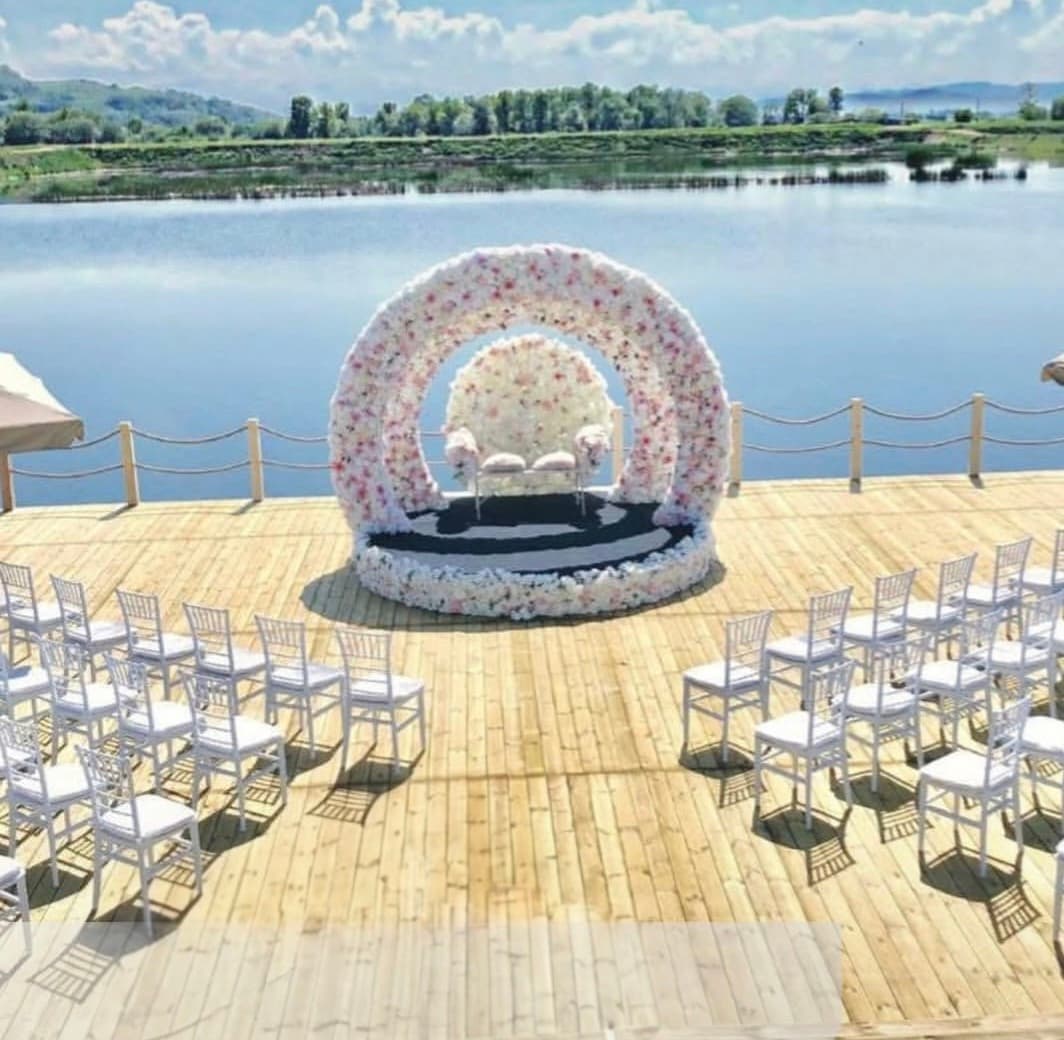 The floral ceremony arch and guest chairs on the lakeside deck at Domeniile Streiului