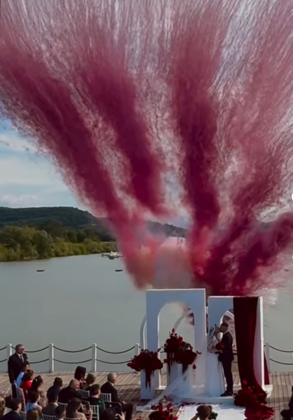 Deep-red colour cannons erupting over a lakeside ceremony at Domeniile Streiului
